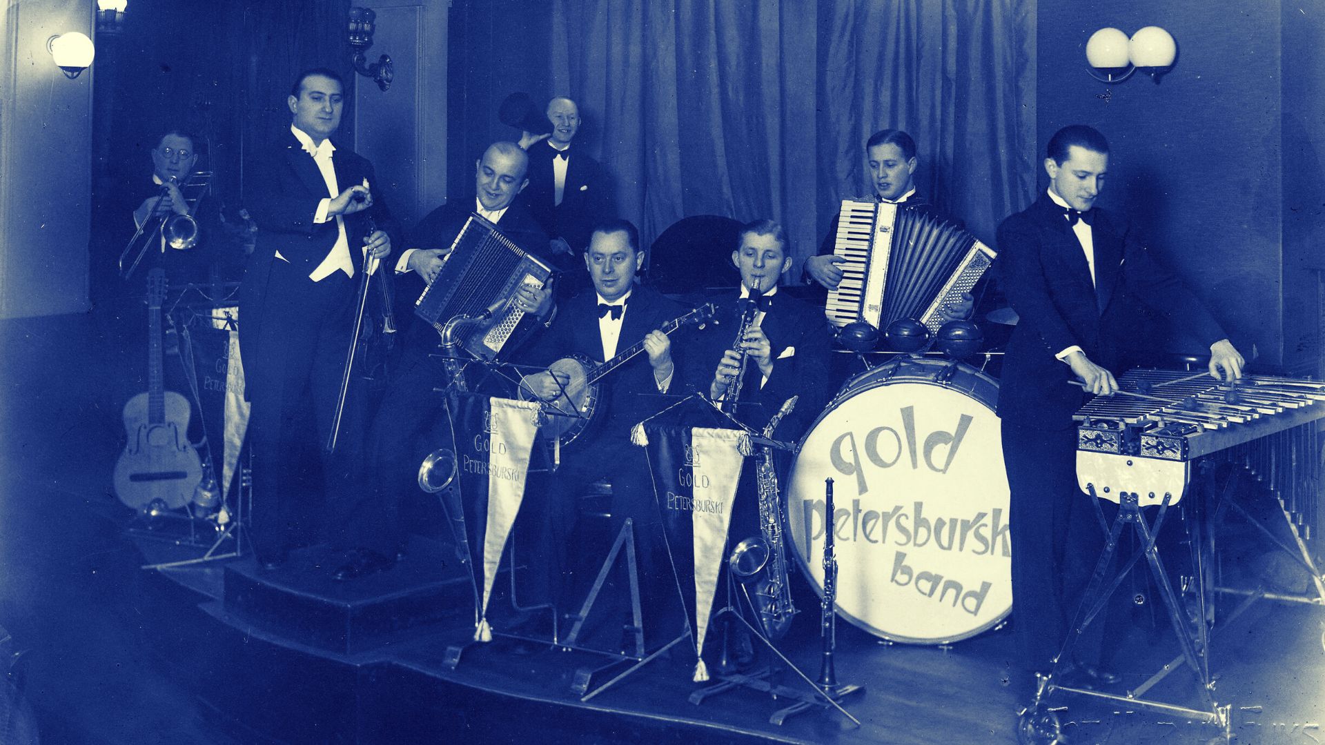 Czarno-biała fotografia w ocieniach błękitu przedstawia muzyków orkiestry Gold Petersburski Band podczas występu